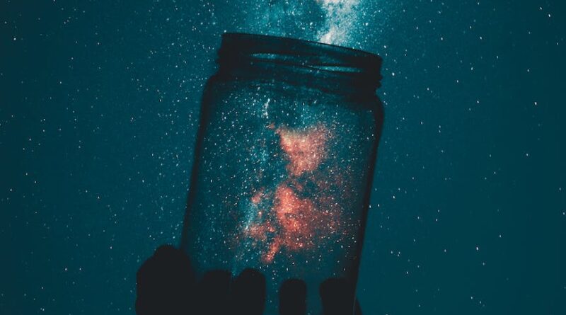 creative photo of person holding glass mason jar under a starry sky